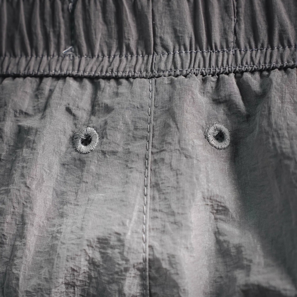 Stone Island light gray shorts front with two metal-rim buttons and seam detail