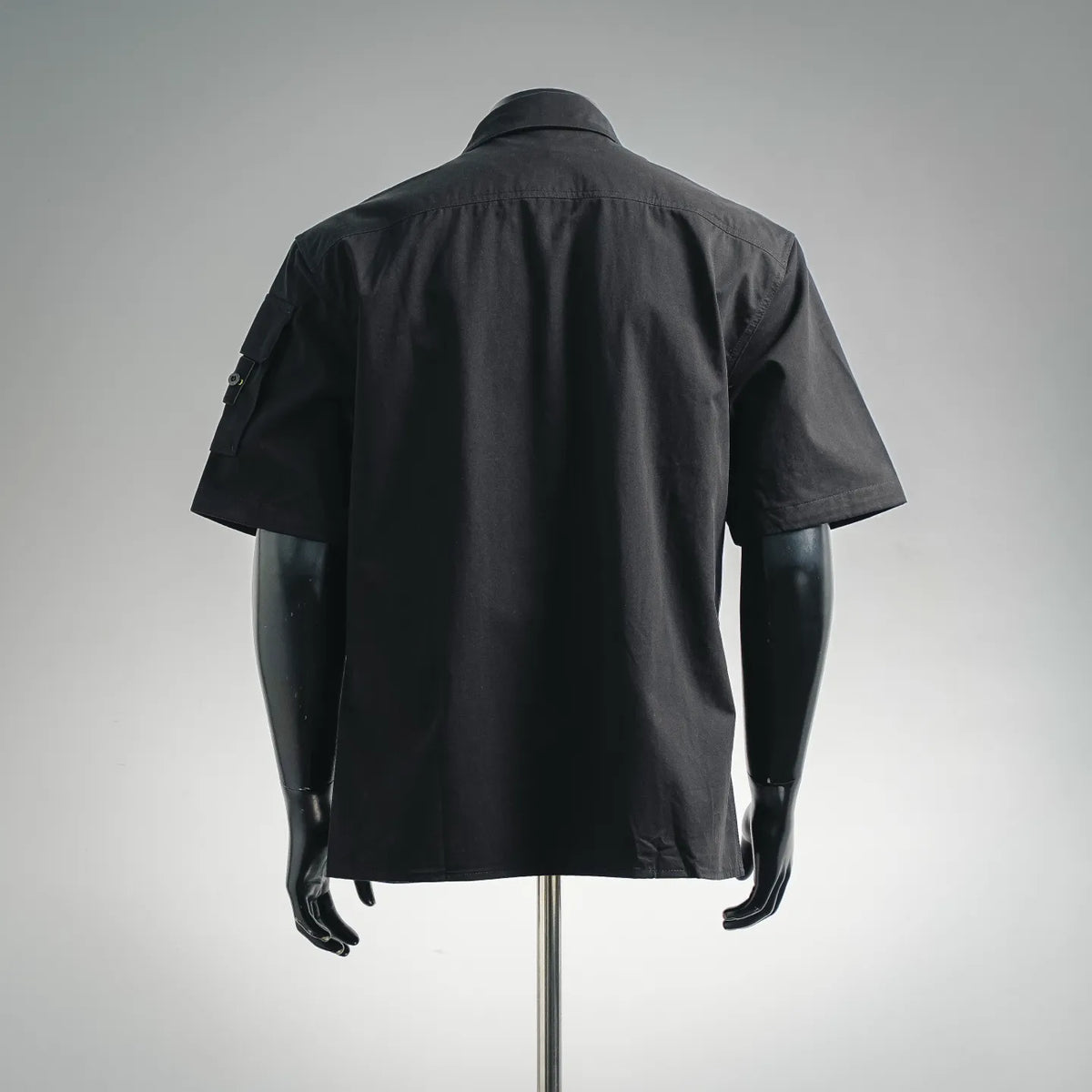 Back view of black short-sleeve button-up shirt with small sleeve patch