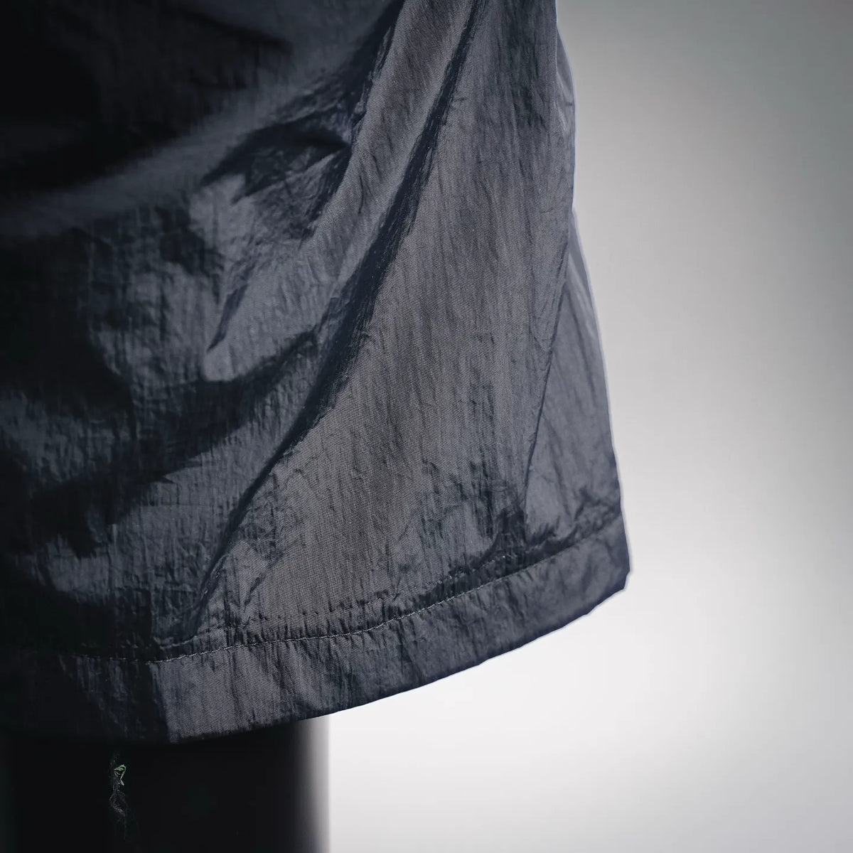 Stone Island dark shorts hem detail with crinkled fabric and stitched edge