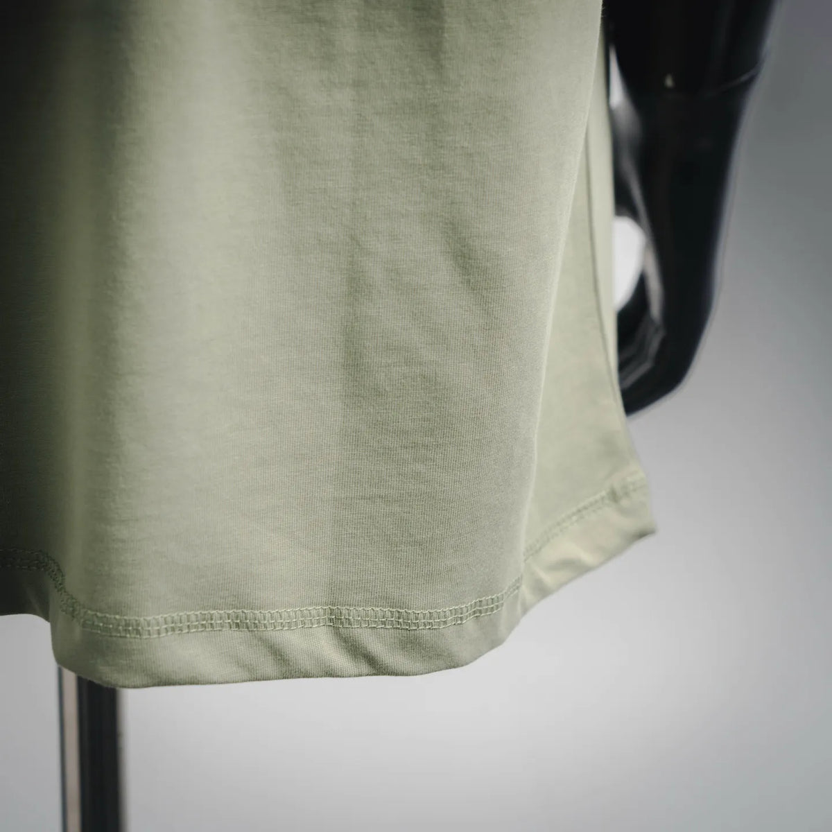 Stone Island short-sleeve T-shirt hem closeup, light green stitched bottom