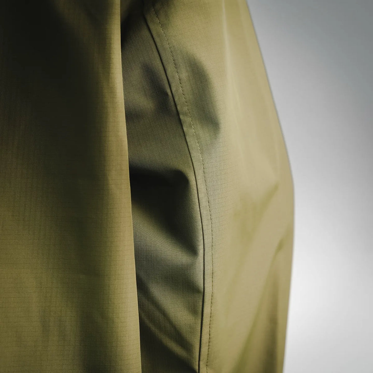 Olive green coat fabric and side seam close-up with stitched panel lines