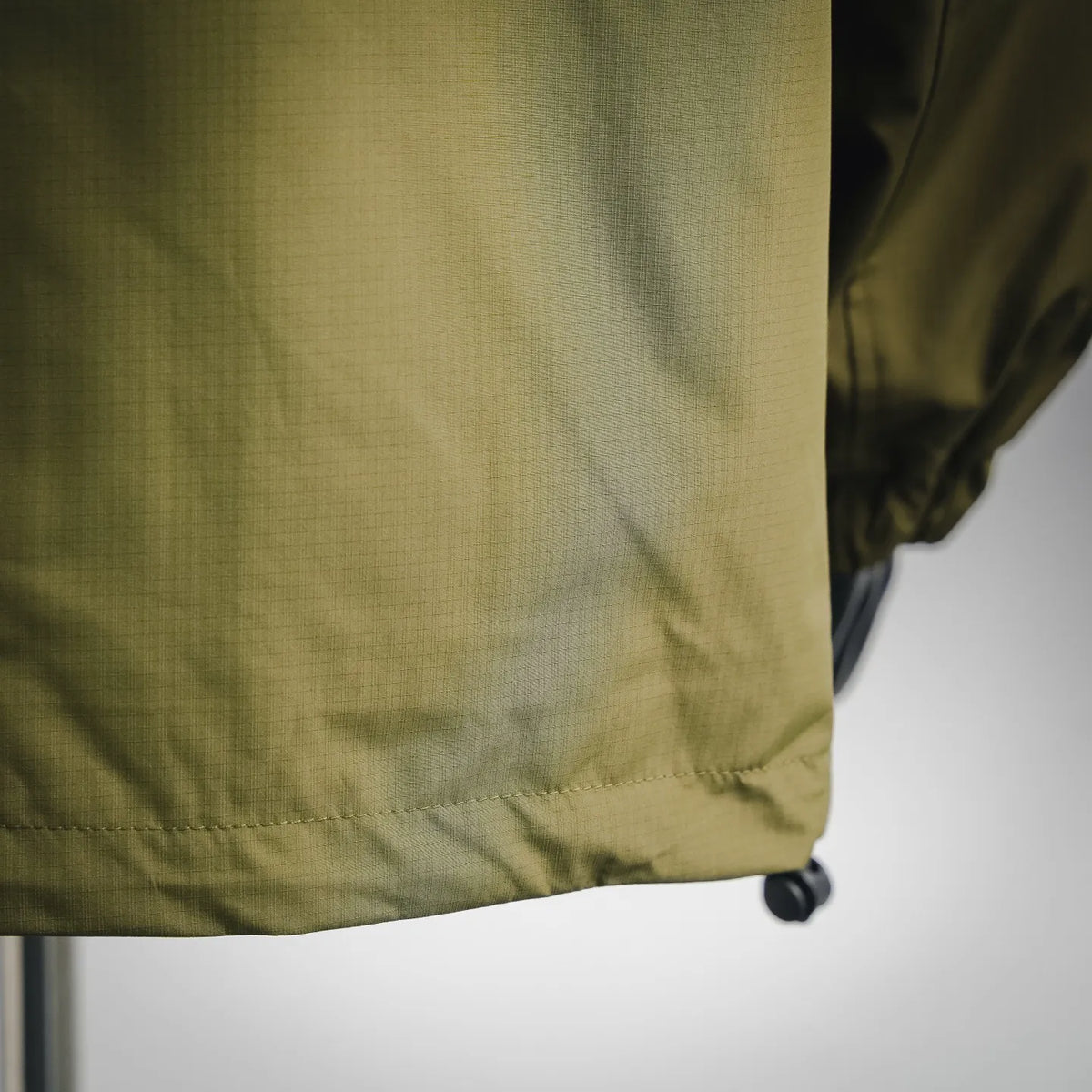 Olive green coat hem with elastic cuff and small drawcord stopper