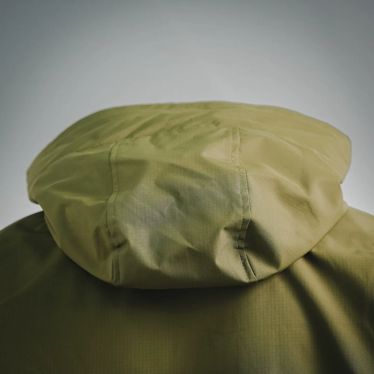 Olive green coat hood close-up with gathered seam and layered fabric