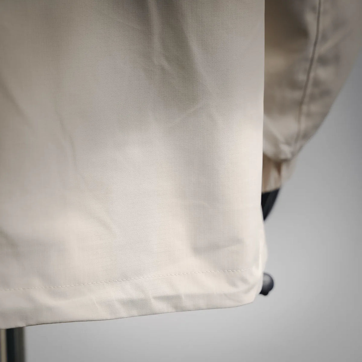 White coat hem with stitched panel and small black attachment loop
