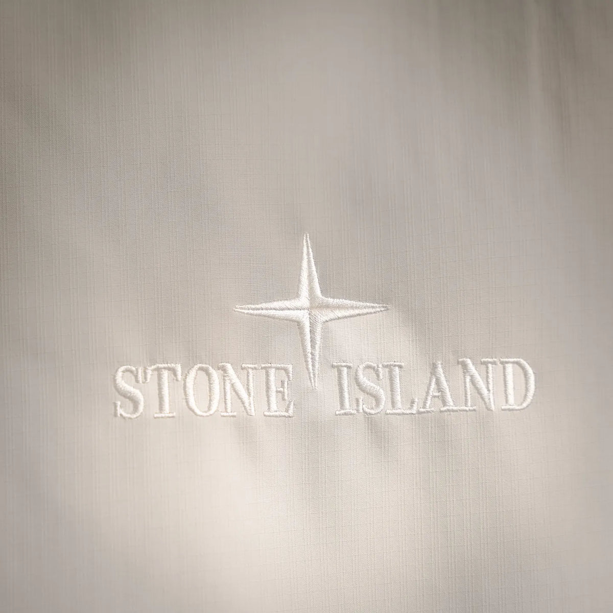 Stone Island logo on white coat fabric