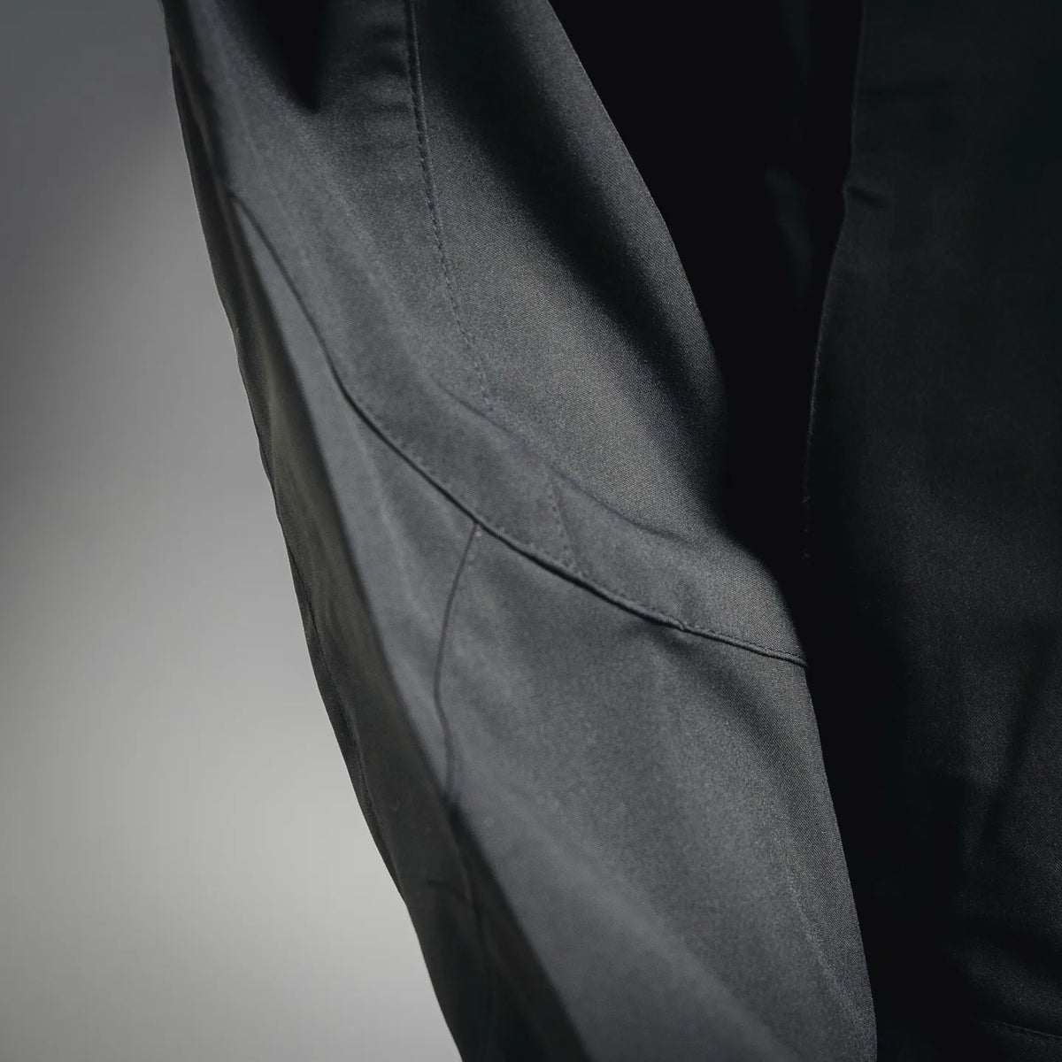 Stone Island coat side seam with curved pocket panel, dark fabric.
