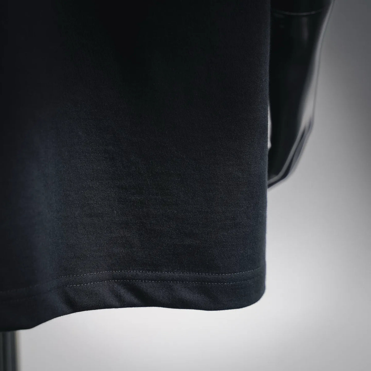 Black T-shirt fabric and stitched hem detail, close-up