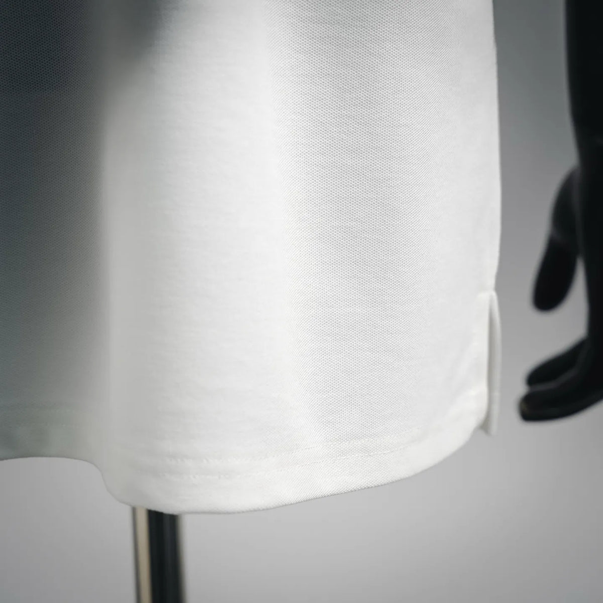 Close-up of white polo shirt fabric texture and curved hem