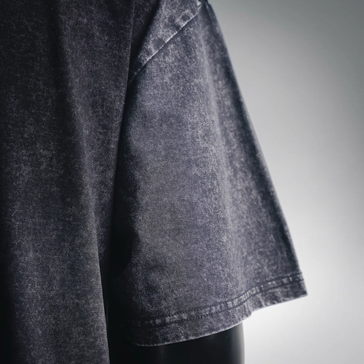 Dark gray short-sleeve t-shirt sleeve cuff with visible seam and faded texture