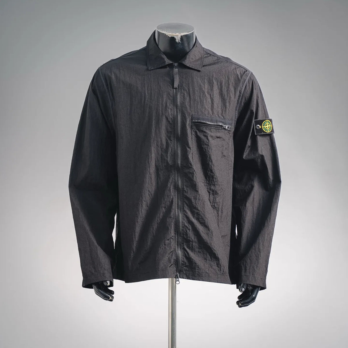 Men's Stone Island dark coat jacket with stand collar, front zip, and chest pocket.