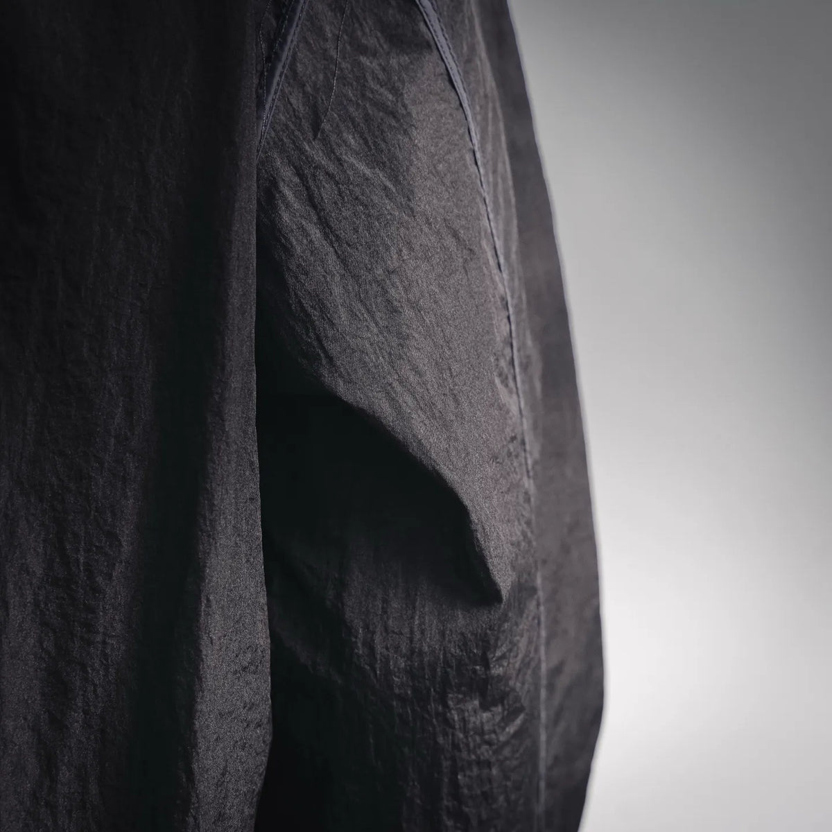 Stone Island dark coat jacket close-up showing textured fabric and angled seam.