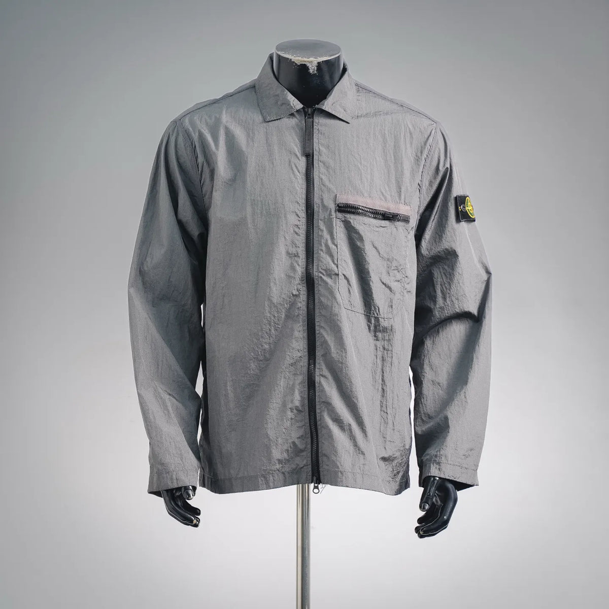Stone Island gray coat on mannequin, buttoned front with chest pocket and sleeve patch