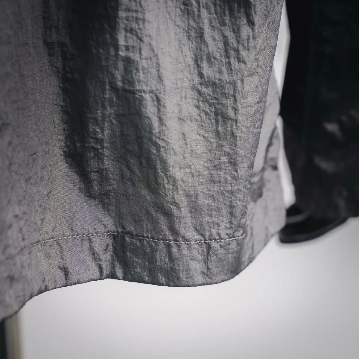 Stone Island gray coat hem close-up with visible stitching and gathered fabric