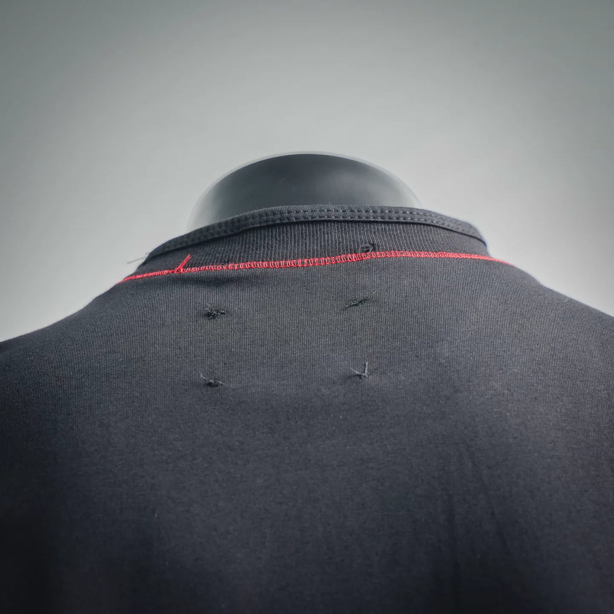 Black T-shirt back close-up with red-trim collar and small fabric marks