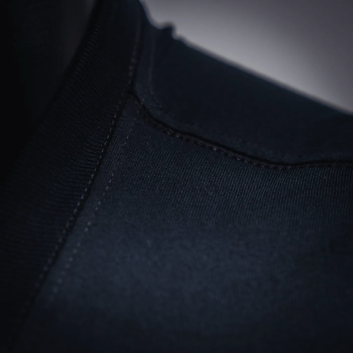 Close-up of ribbed crew neckline stitching on black T-shirt