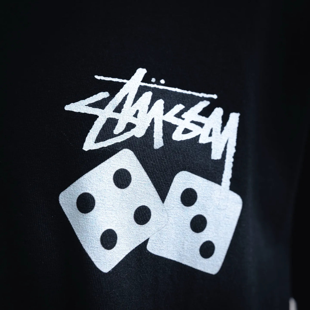 Close-up of white Stussy dice graphic print on black T-shirt