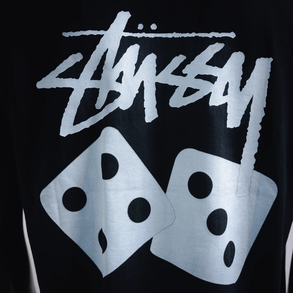Close-up of large white Stussy dice graphic print on black T-shirt