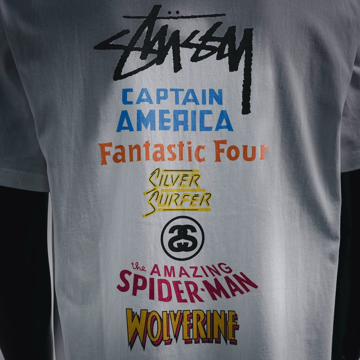 White T-shirt back graphic with Stussy logo and multicolor character text