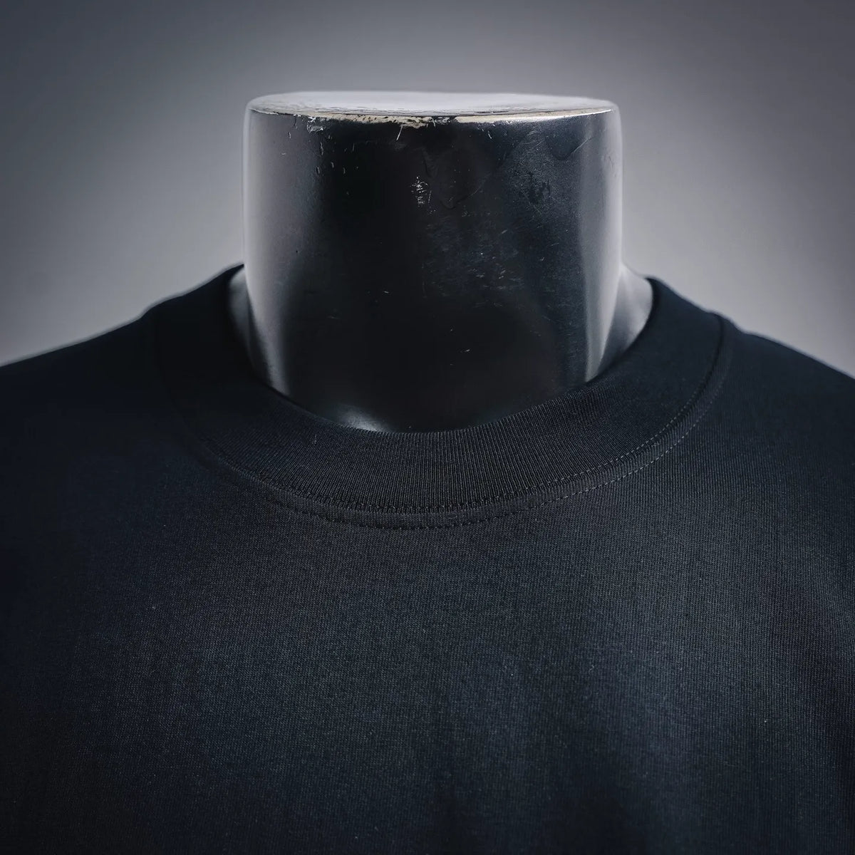 Black short-sleeve T-shirt neckline close-up; ribbed crew collar.