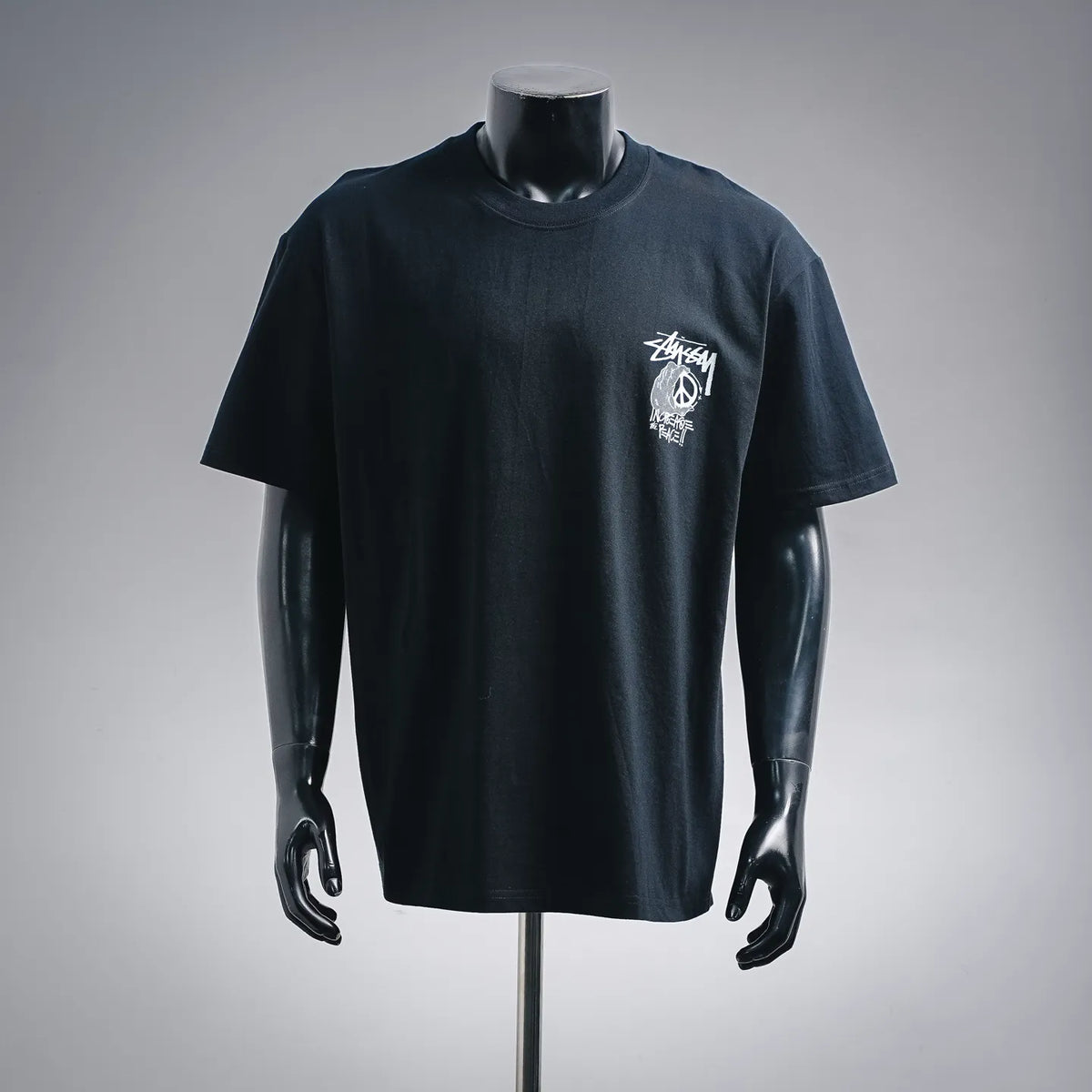 Black crew-neck T-shirt with small white Stussy logo graphic on the chest
