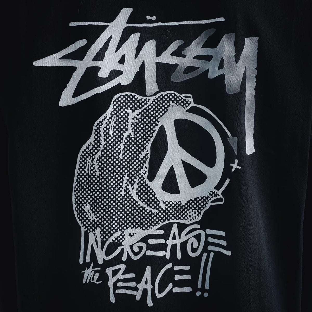Black T-shirt with white peace-symbol style graphic and Stussy text print