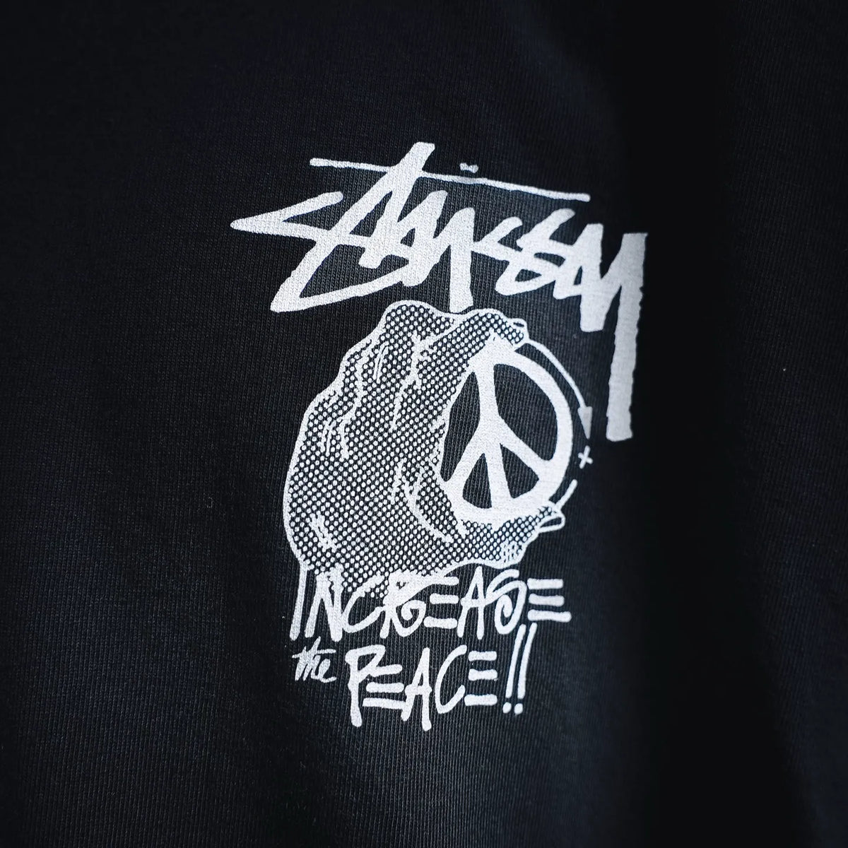 Black crew-neck T-shirt with white Stussy and peace graphic print