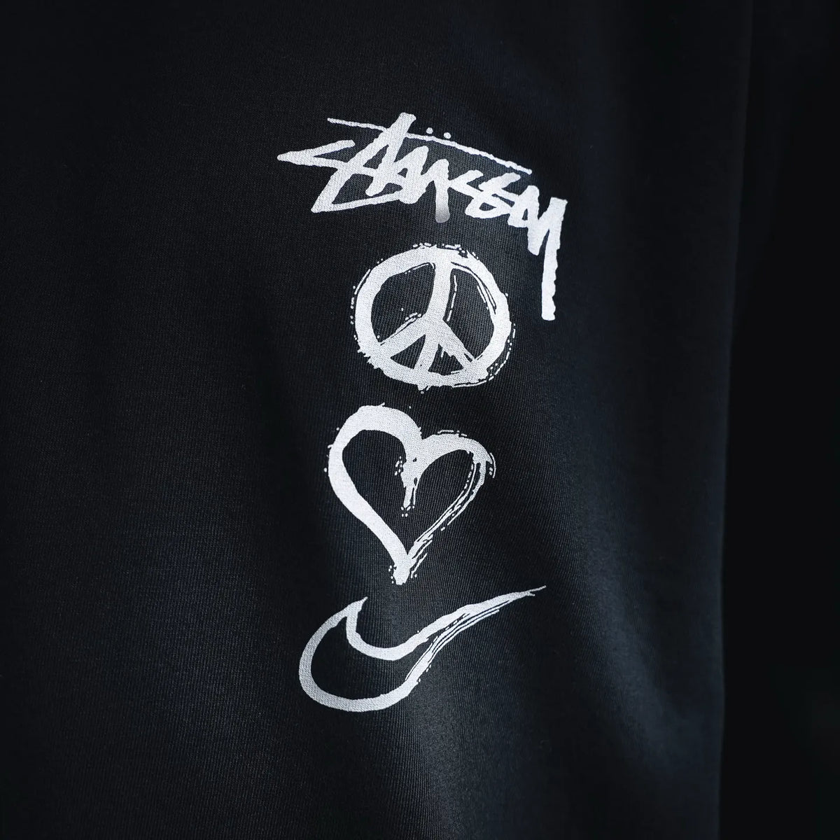 Black T-shirt graphic print close-up with peace heart and Nike swoosh
