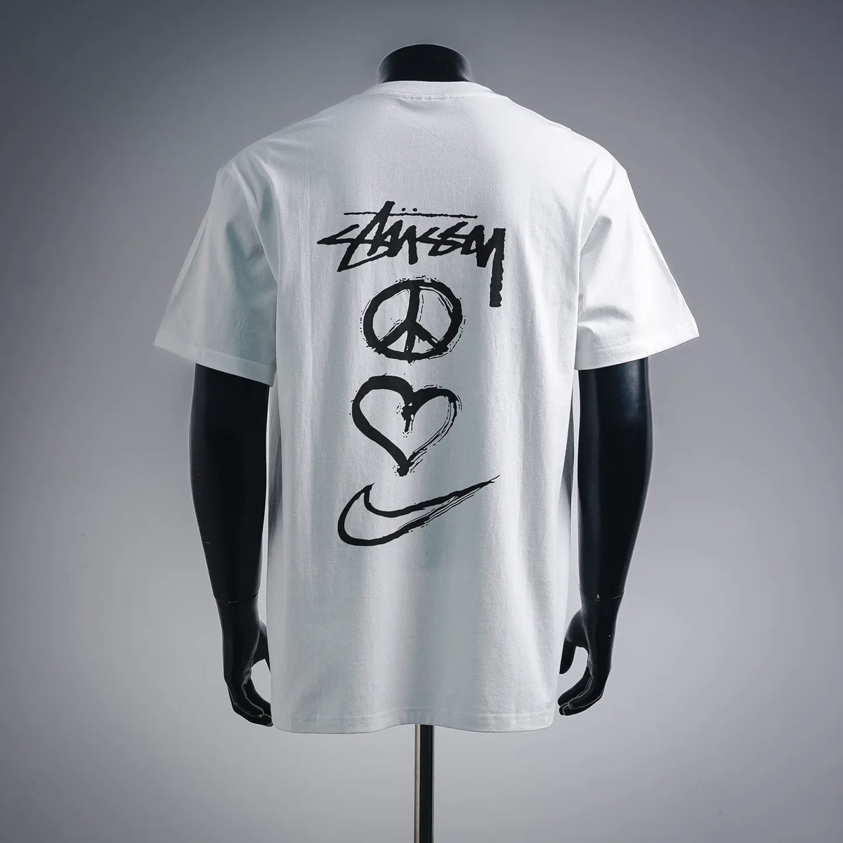 White T-shirt with Stussy back graphic featuring peace, heart, and swoosh