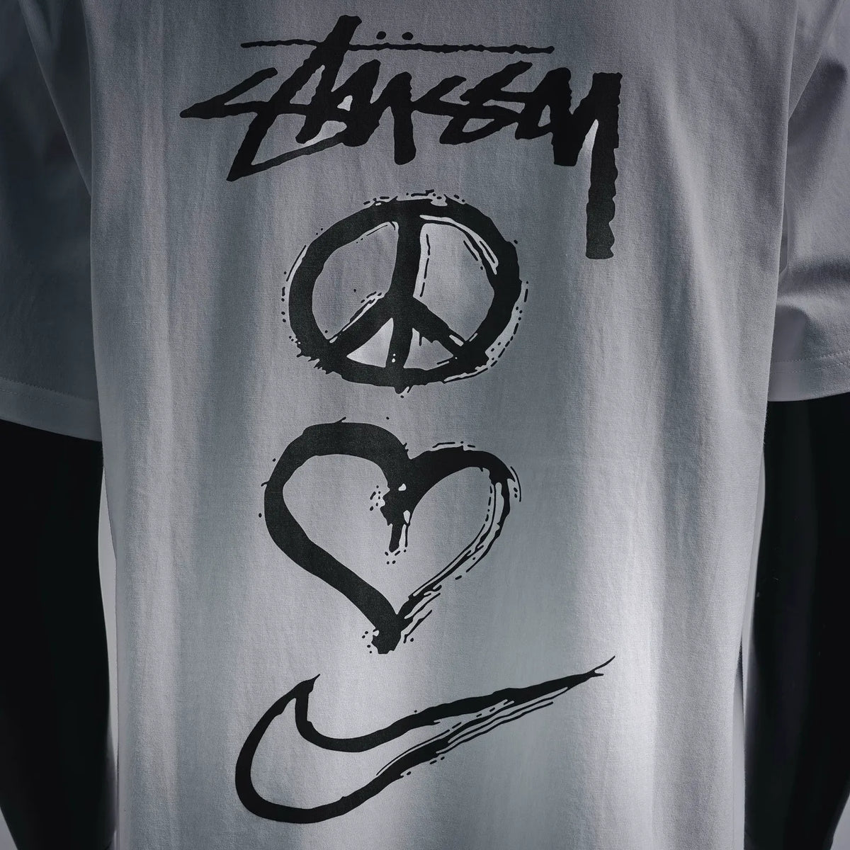 Close-up of Stussy peace-heart graphic on white T-shirt