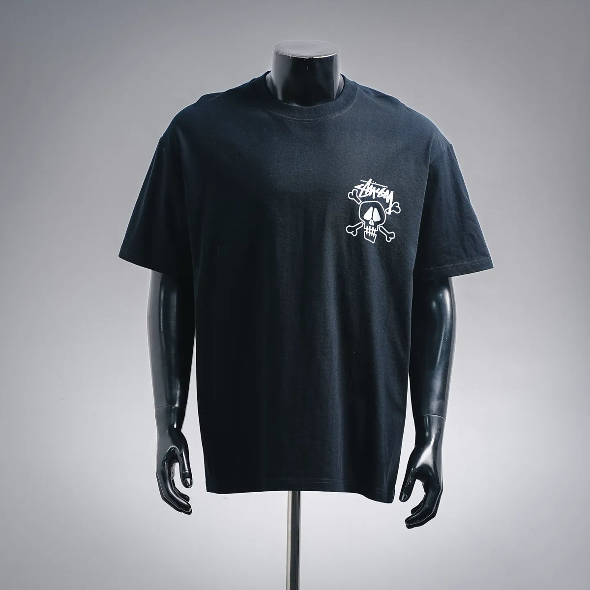 Black Stussy T-shirt with white skull-and-pipes graphic on chest