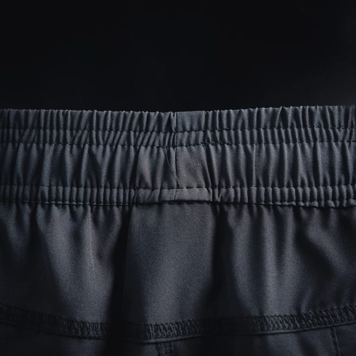Dark gray shorts waistband detail with elastic ruching and seam lines