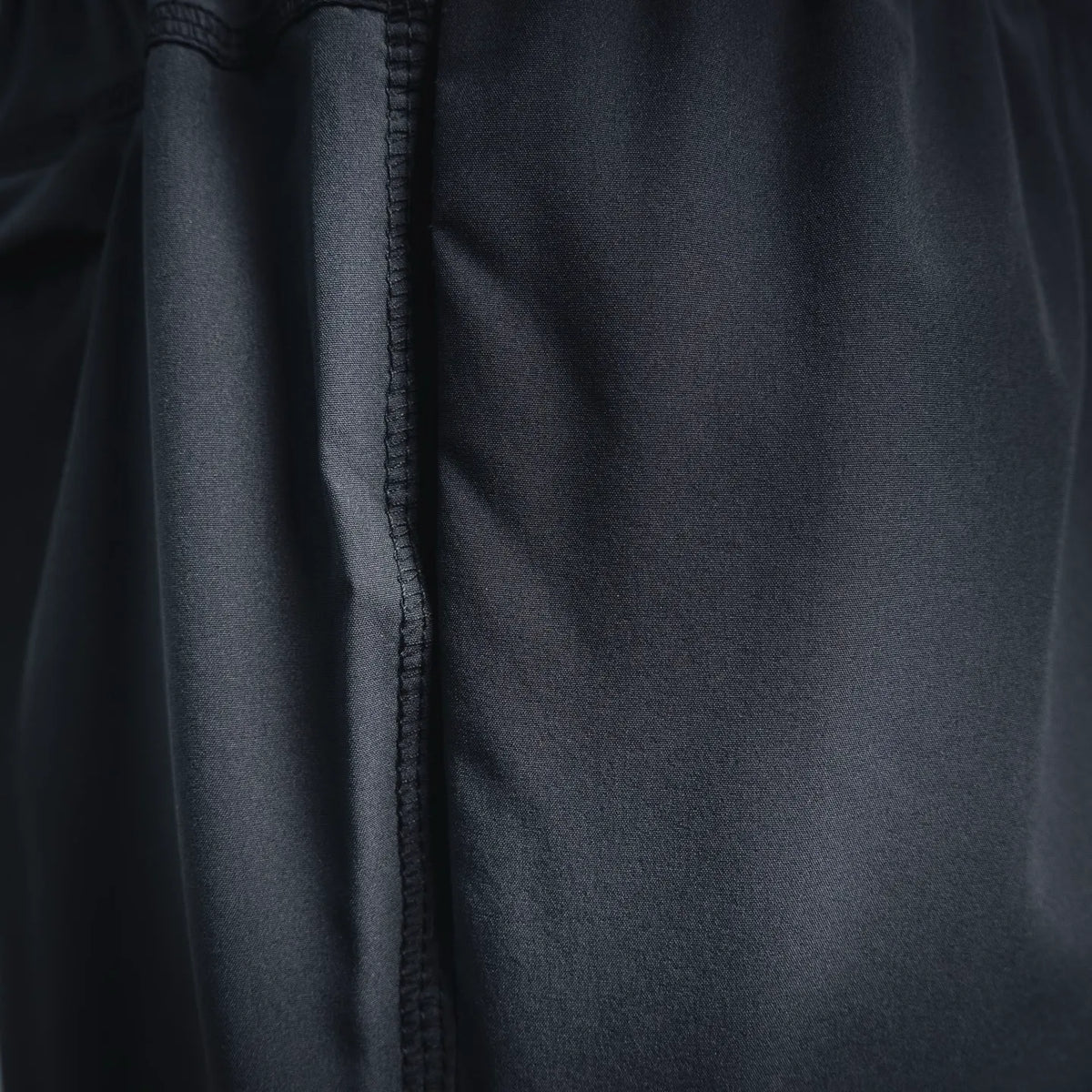 Dark gray shorts side panel with stitched seam and smooth fabric