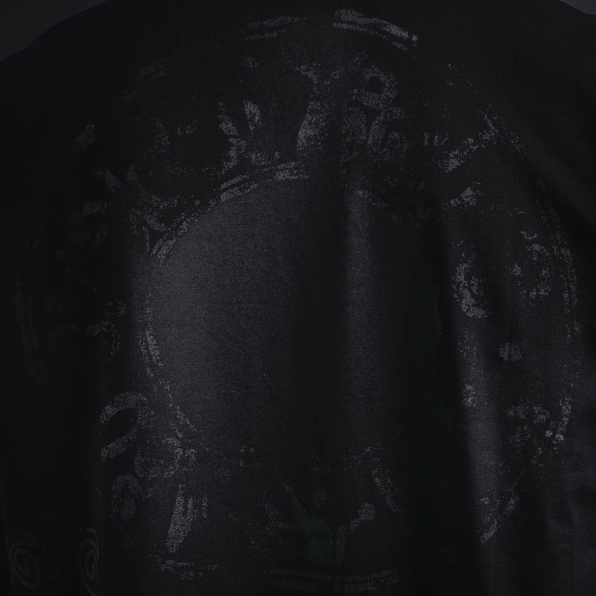 Stussy black T-shirt front graphic close-up with faded skull and symbols