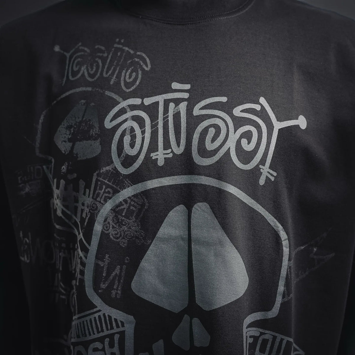 Stussy black T-shirt front print close-up with skull and peace-sign graphic