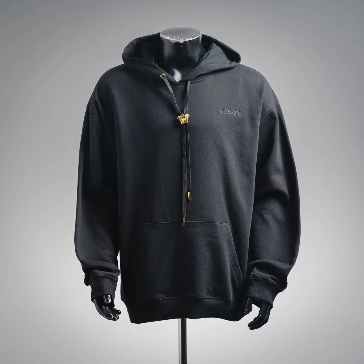 Black zip-up hoodie with drawstring hood and gold Medusa zipper pull