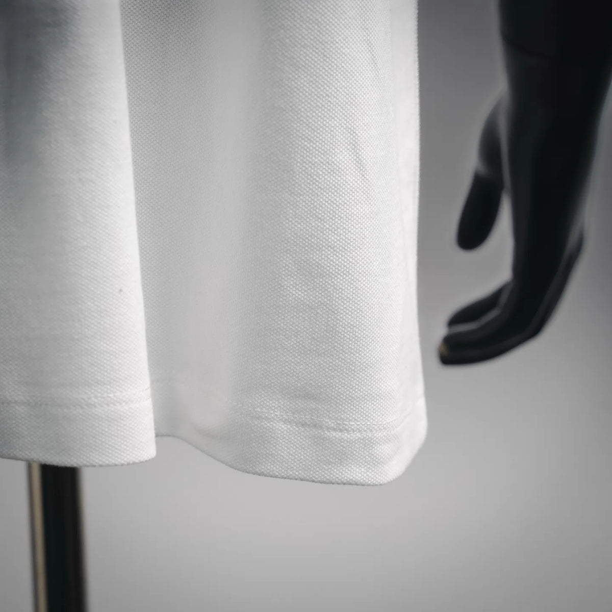 White polo shirt hem detail with textured fabric and straight bottom edge