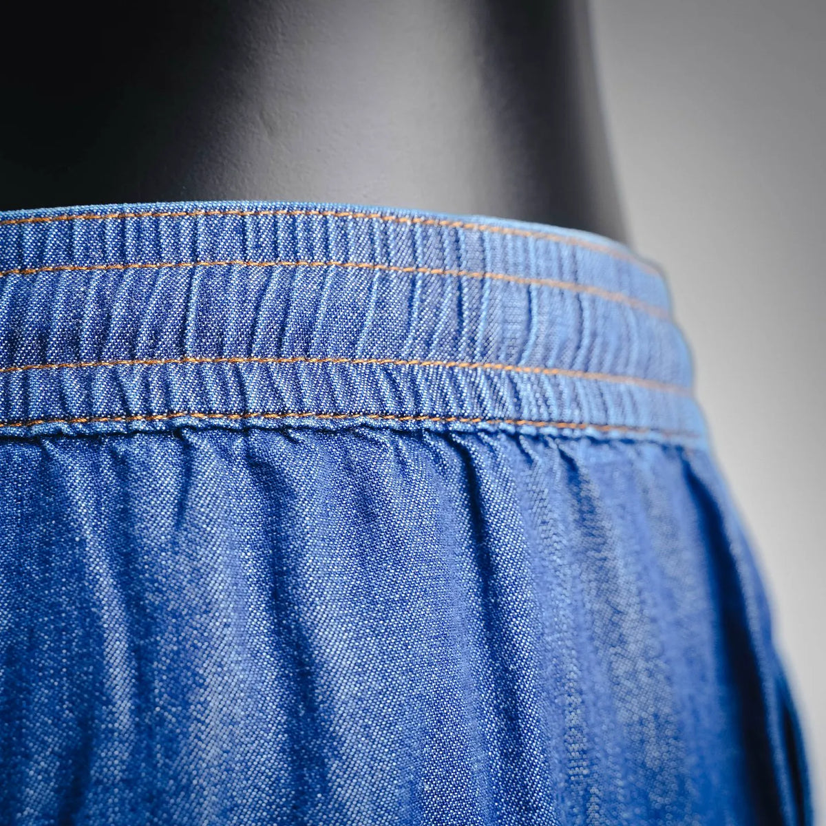 Blue denim shorts waistband with orange contrast stitching