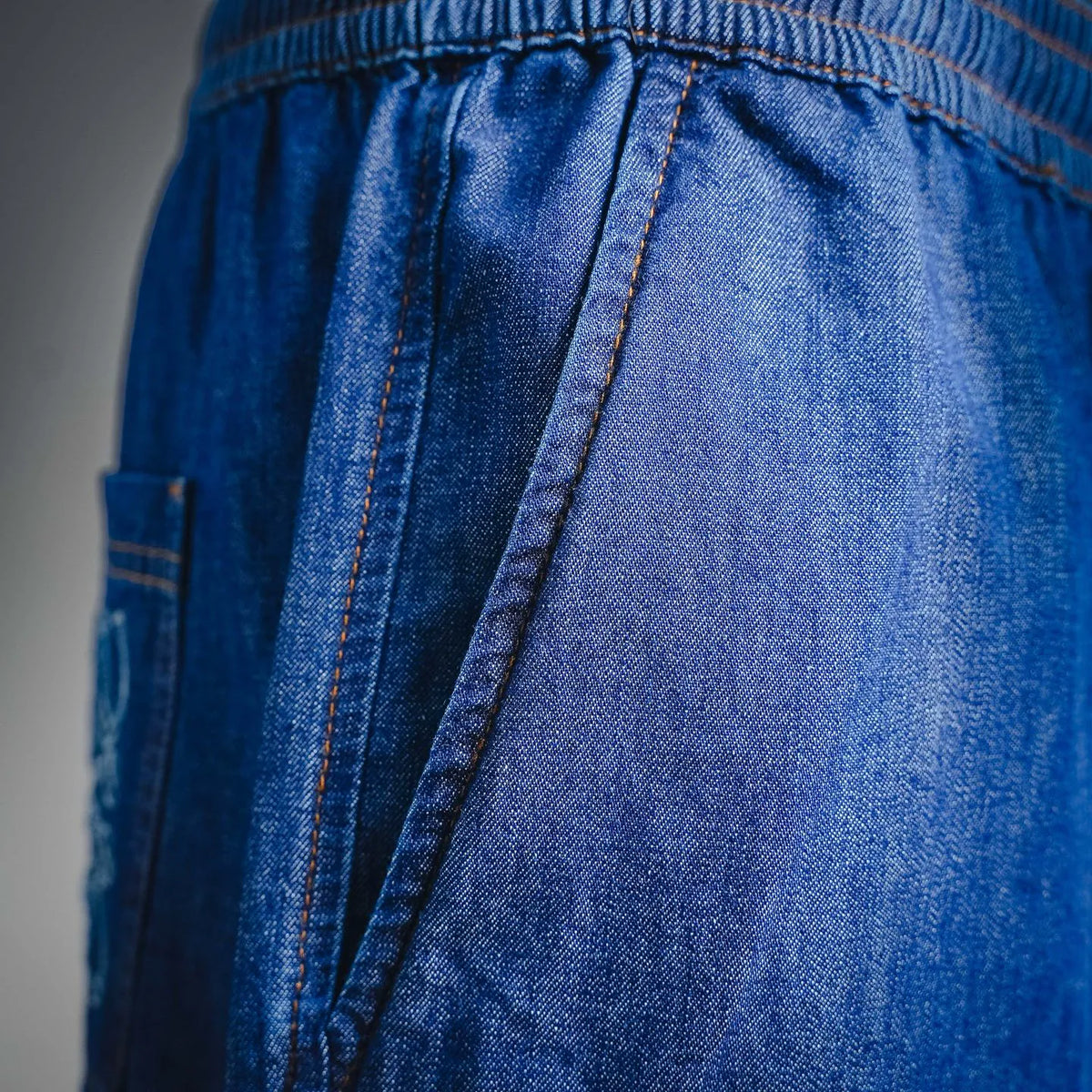 Blue denim shorts front with pleated panel and orange seam stitching