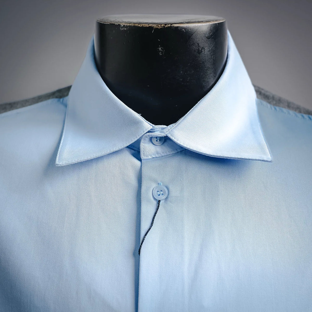 Light blue dress shirt collar with button placket and small emblem button