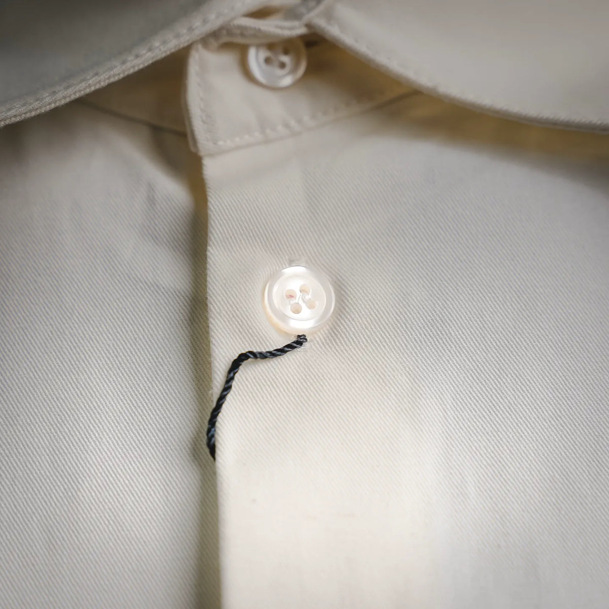 White button and stitched placket close-up on a long-sleeve shirt