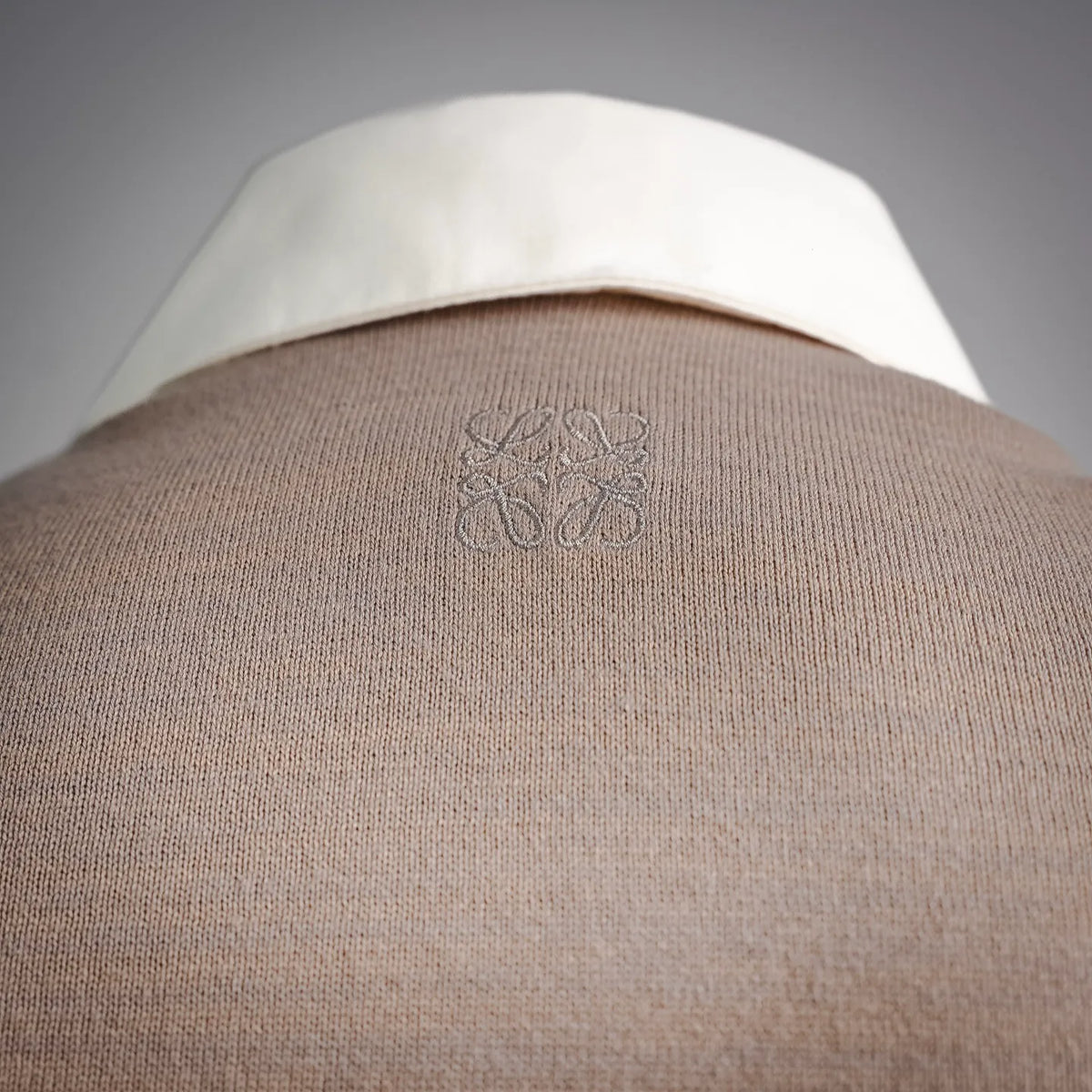 Beige knit fabric with small embroidered logo on the collar area