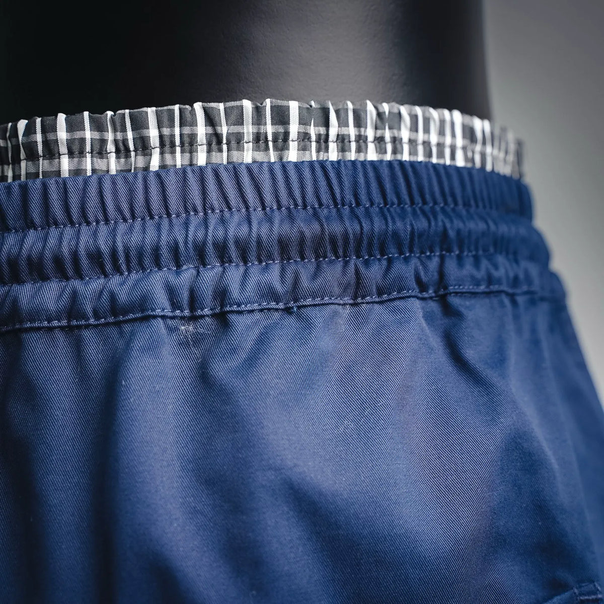 Blue shorts waistband close-up with elastic and check trim