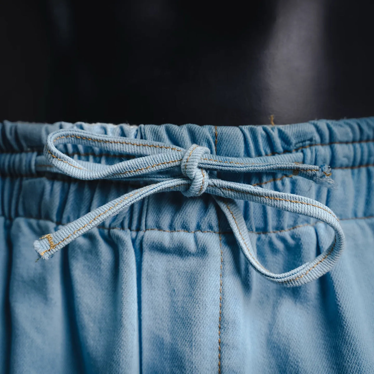 Light blue denim pants with drawstring tied at the elastic waistband