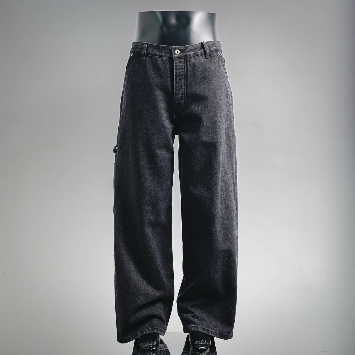 Dark denim LOEWE pants with buttoned waistband and straight legs on mannequin