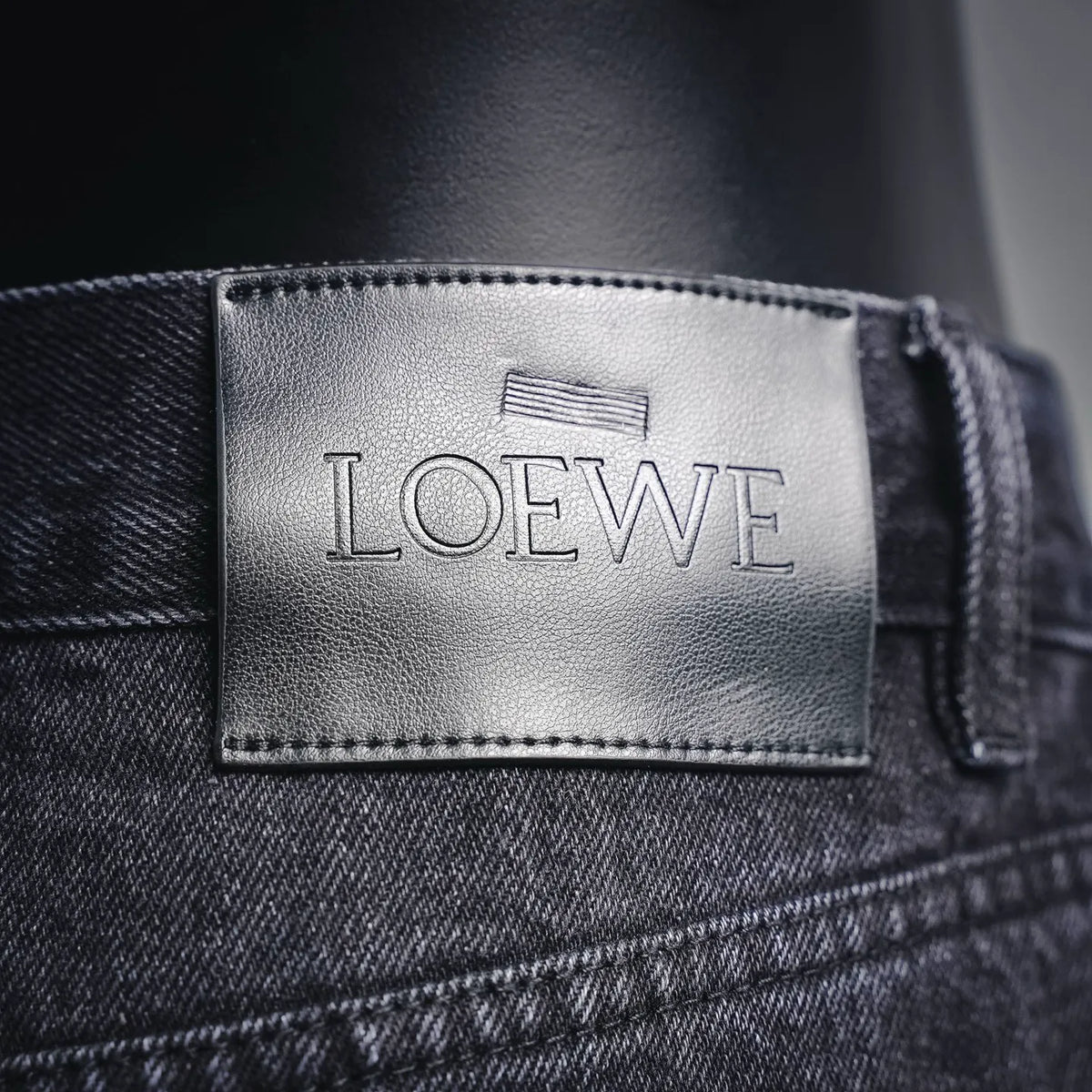 LOEWE logo leather waistband patch on dark denim pants