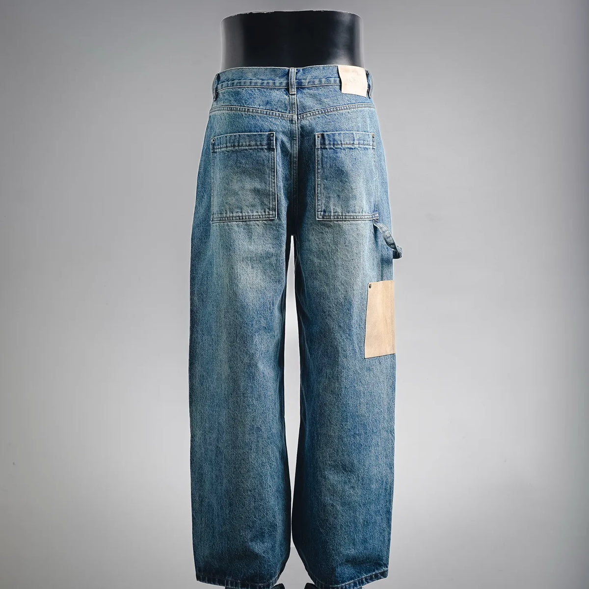 LOEWE denim pants, back view in light blue with beige patch detail on leg.