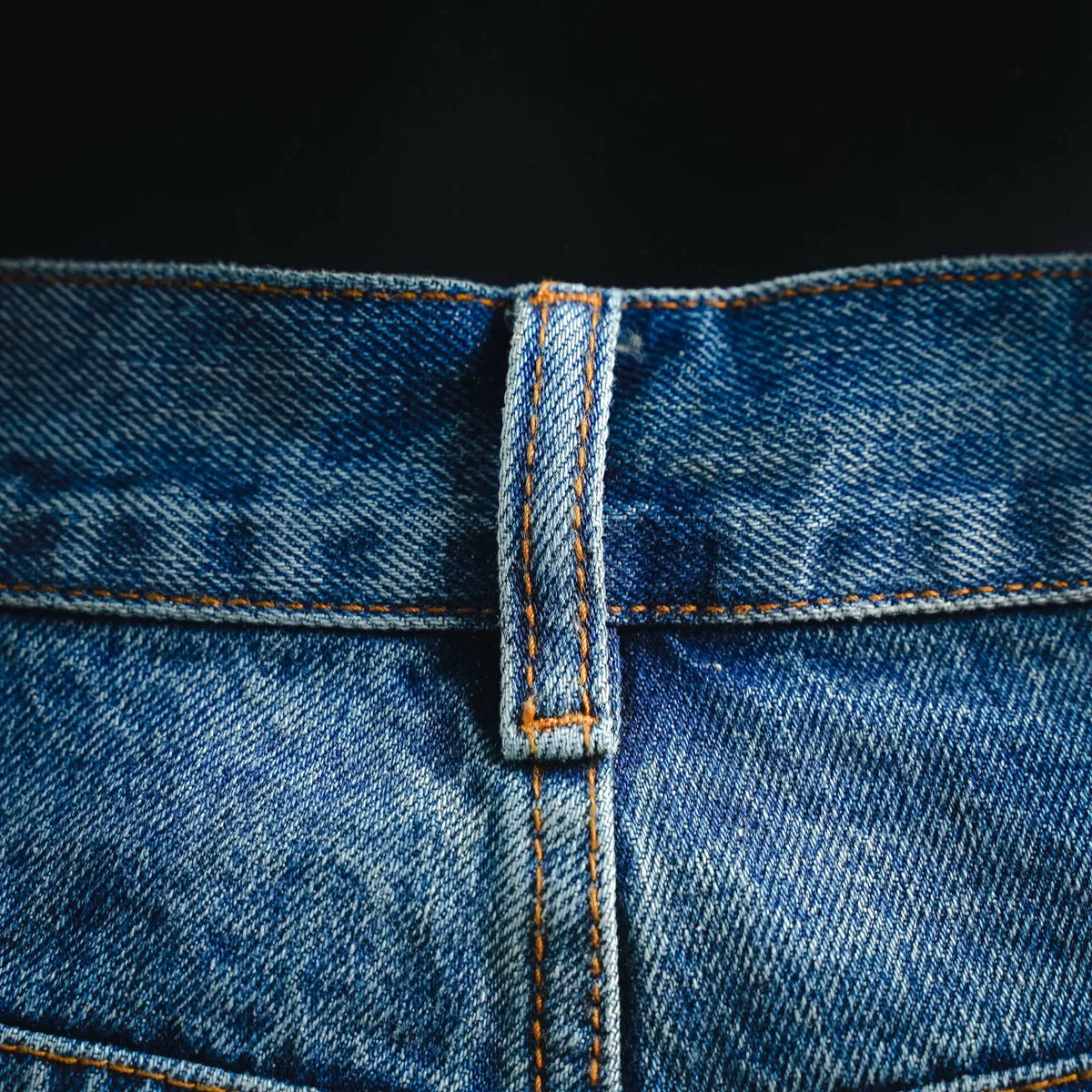 LOEWE denim pants fly area with button closure and contrast orange topstitching.