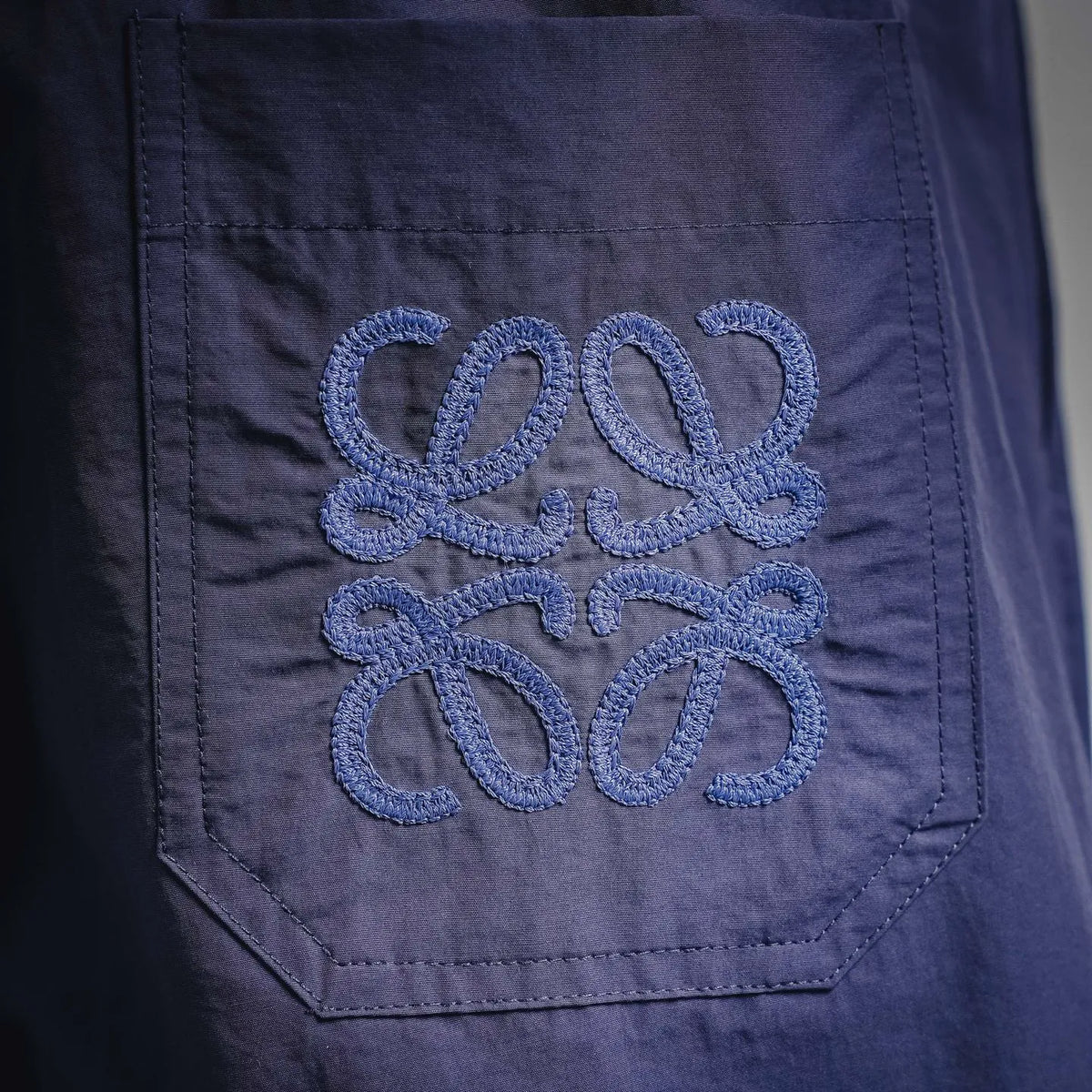 Dark blue shorts with embroidered blue logo patch on front pocket