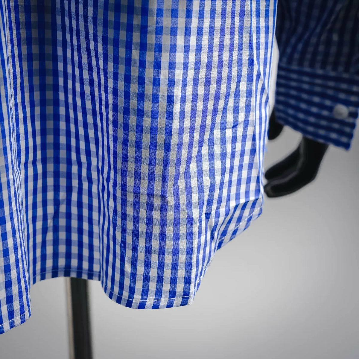 Blue and white check shirt hem and side seam detail.