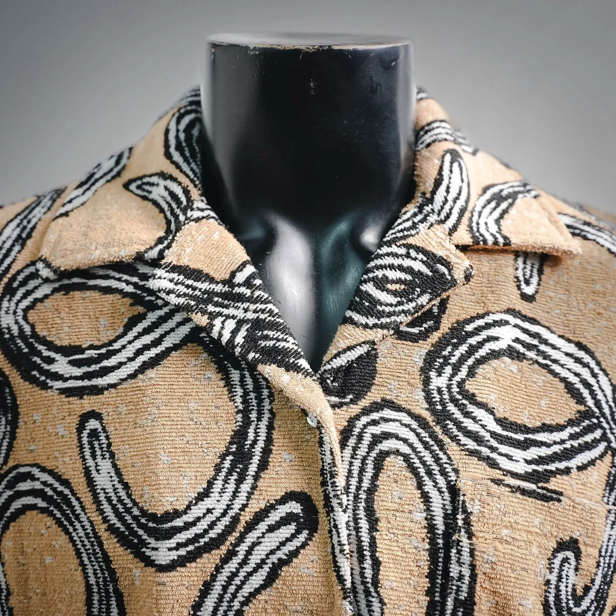 Short-sleeve button-up shirt with open collar and abstract black-and-tan pattern
